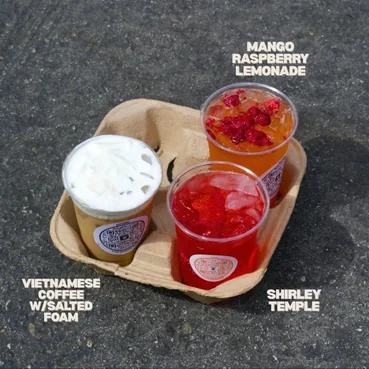 Three drinks on a tray, labelled mango raspberry lemonade, Vietnamese coffee with salted foam and Shirley Temple